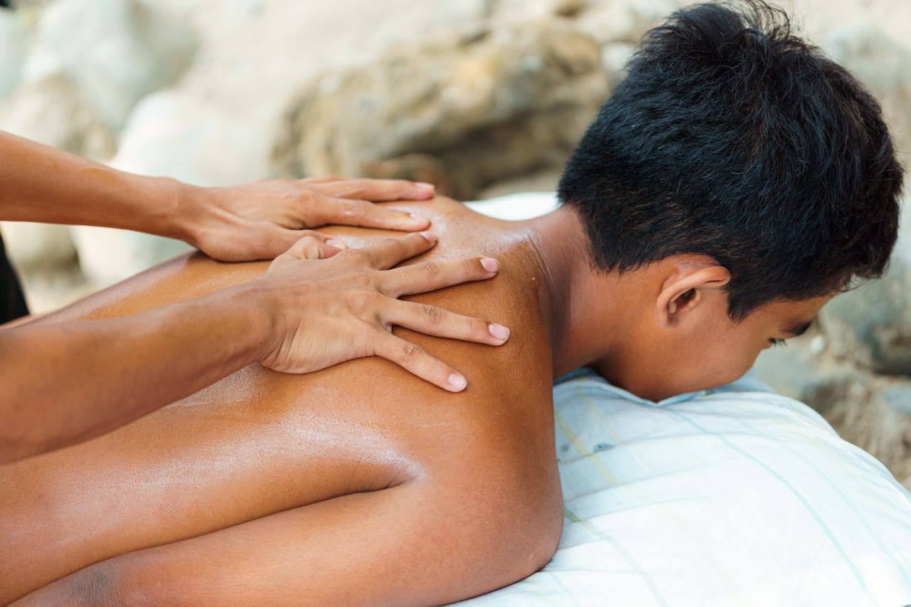 services-05 Person receiving a back massage outdoors, emphasizing relaxation and wellness.