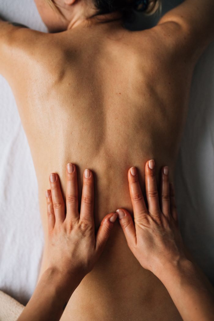 our-value Hands massaging a person's back for relaxation in a calming indoor setting.