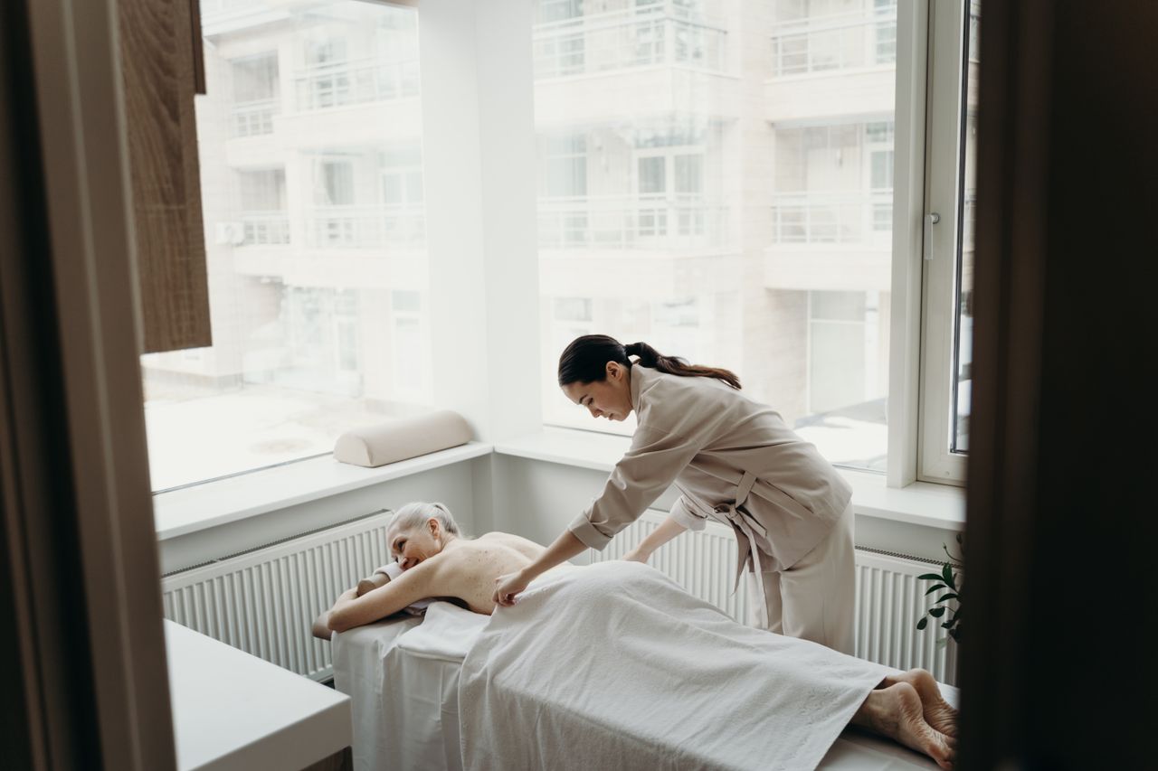 services-09 A relaxing spa day with a woman receiving a massage from a therapist indoors.