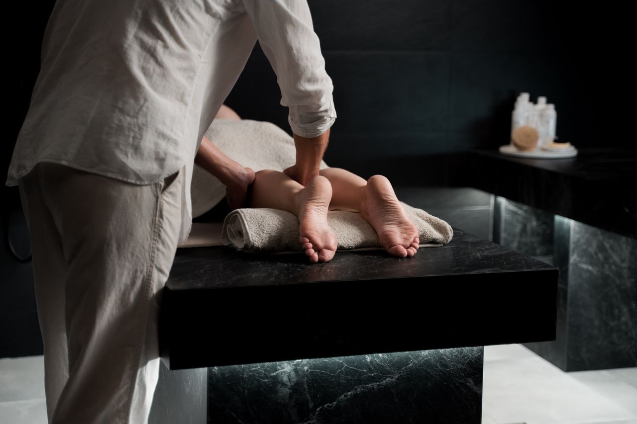 our-mission A therapist providing a serene foot massage for relaxation in a modern spa setting.